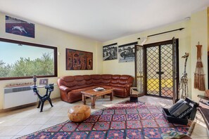 Un soggiorno con un divano in pelle marrone, un tavolino da caffè, un tappeto decorato e un'ampia finestra.