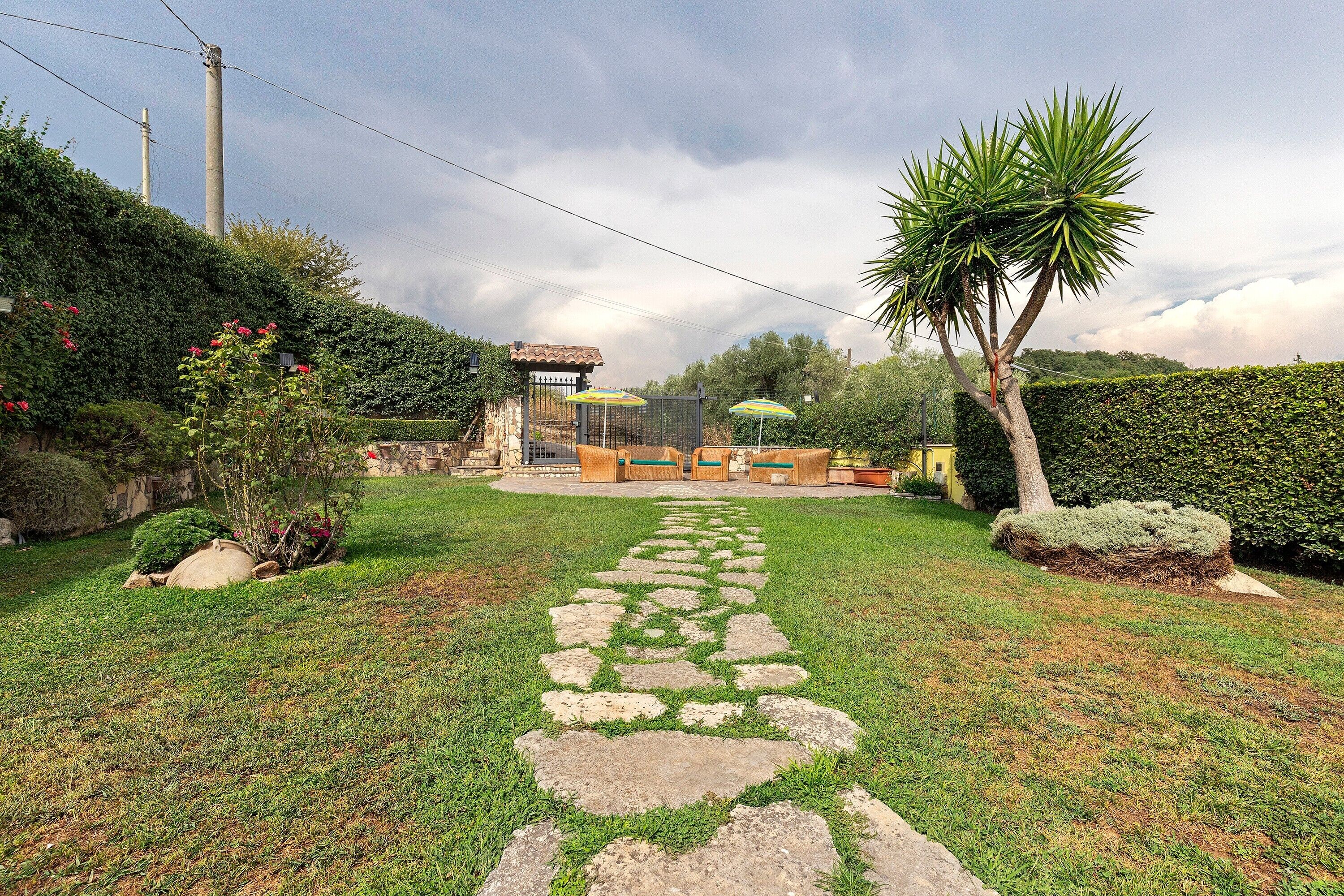 A garden with a stone pathway leading to a seating area with outdoor furniture.