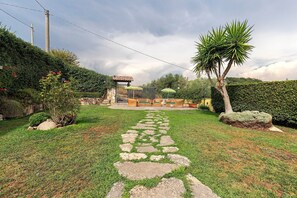 A garden with a stone pathway leading to a seating area with outdoor furniture.