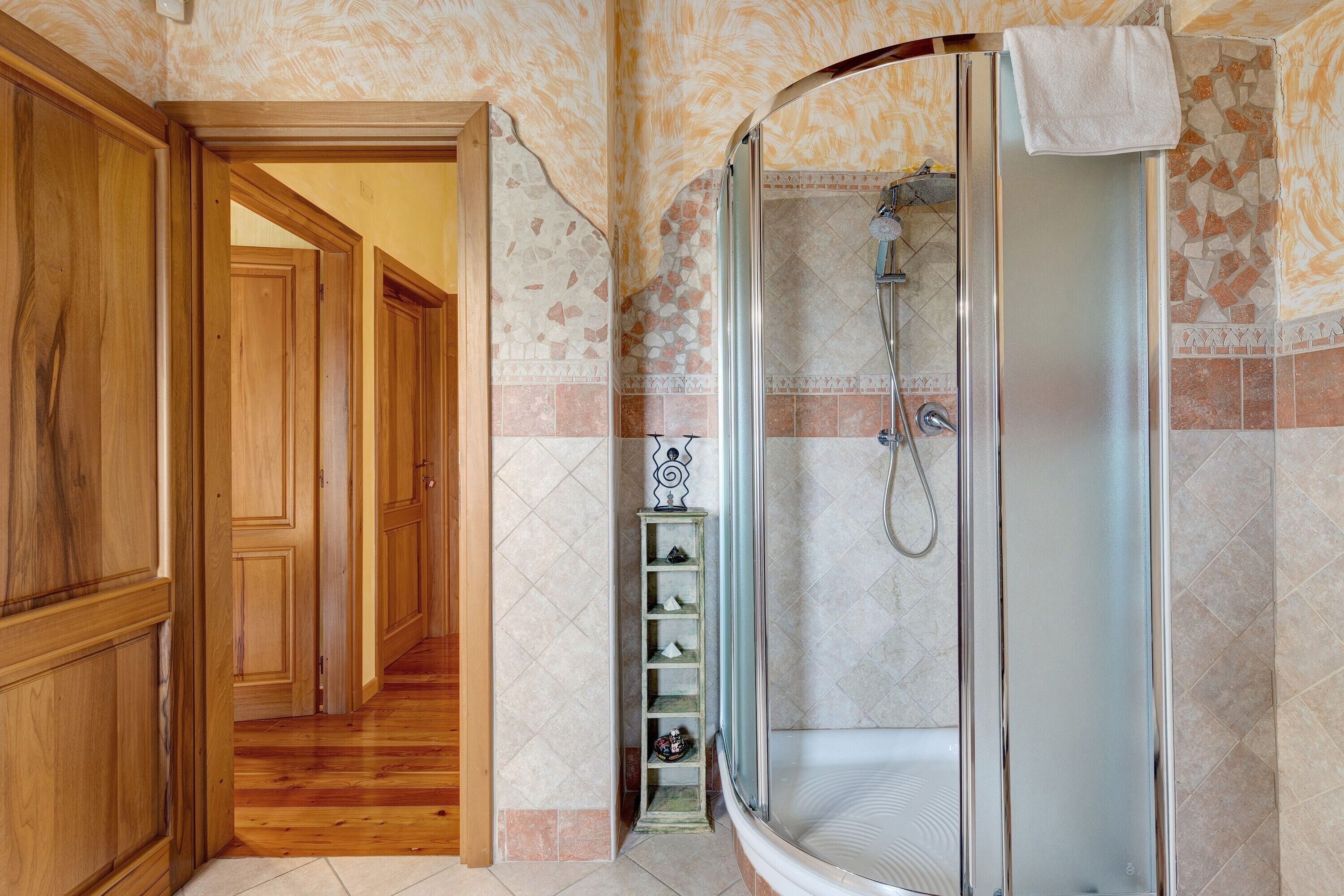 Un bagno con doccia, pareti piastrellate e pavimento in legno.