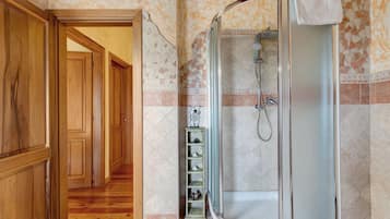 Un bagno con doccia, pareti piastrellate e pavimento in legno.