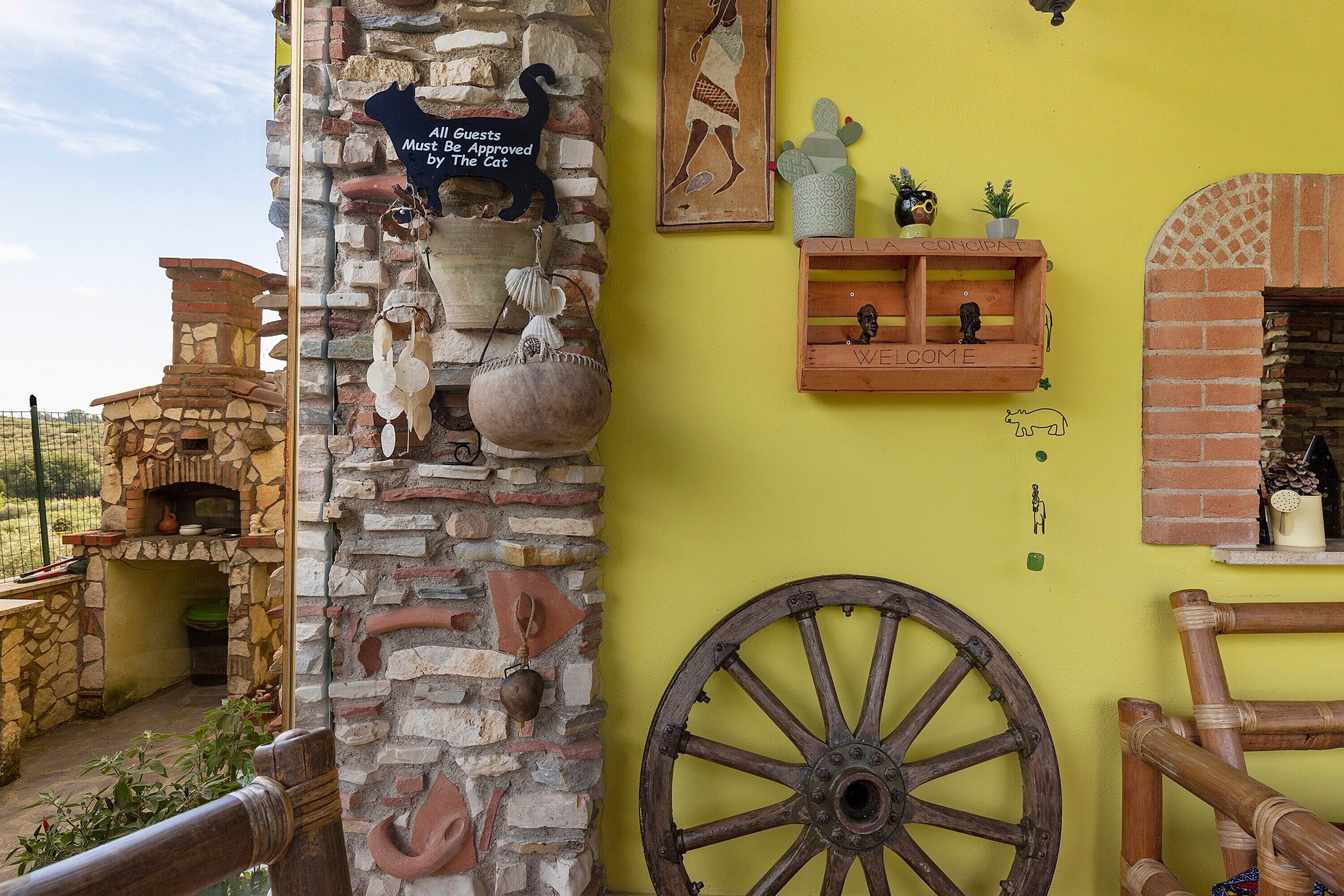 A rustic building with a stone wall, a wooden cart, and a shelf with figurines.