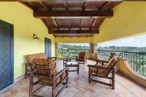A covered outdoor seating area with wooden furniture and a view of the countryside.