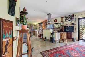 A spacious kitchen with a central island, a dining area with chairs, and a large rug.