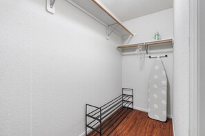 Ein schmaler Korridor mit Holzboden, einem Metallgestell und einer weißen Wand.
