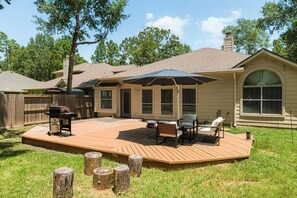 A backyard with a wooden deck, outdoor furniture, a grill, and a covered patio area. - Single Story 4BR Near The Woodlands, Medical, Corporate and Family Friendly (Conroe)