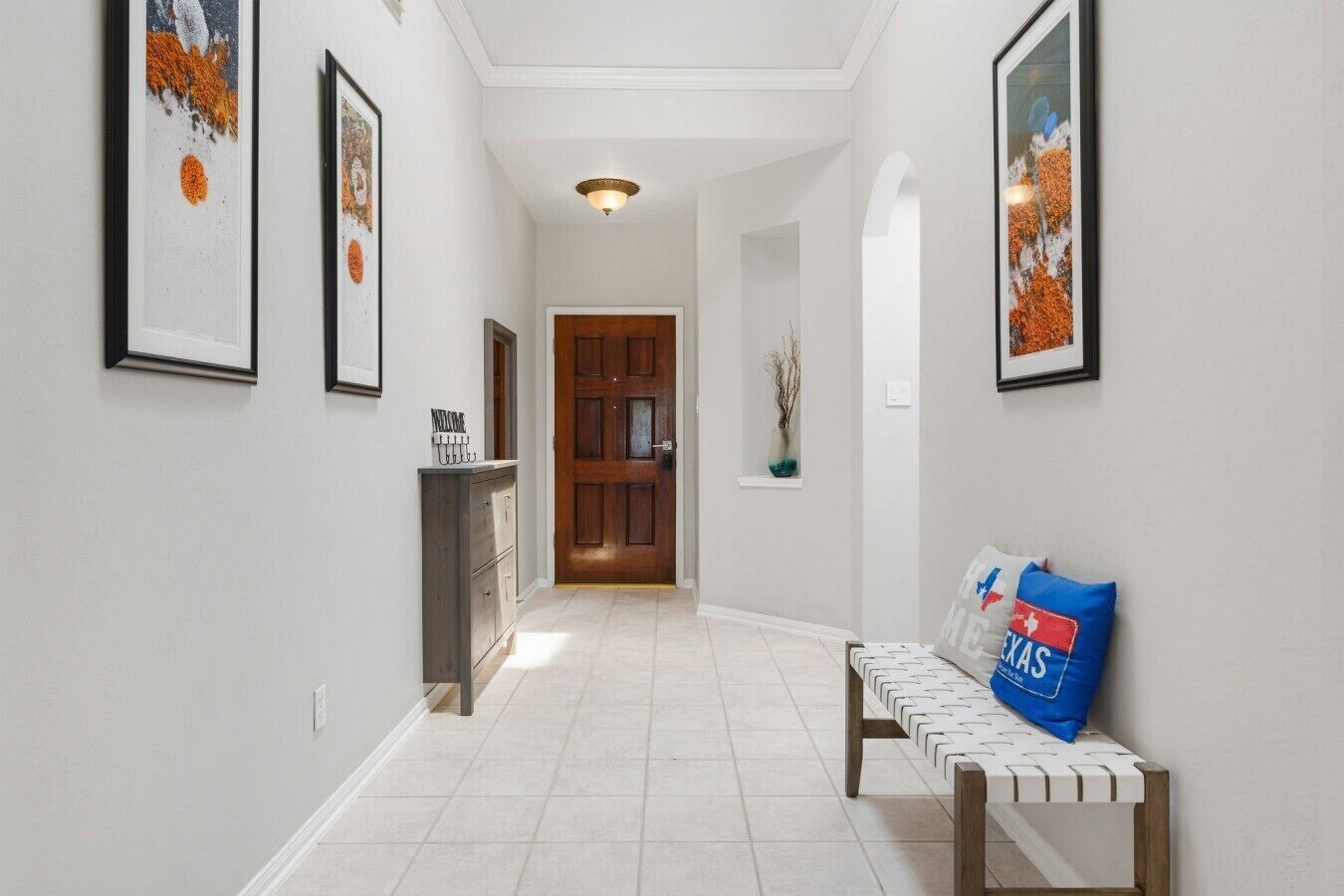 A hallway with a bench, framed artwork, a door, and a cabinet.