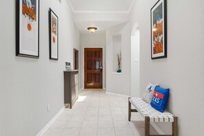 A hallway with a bench, framed artwork, a door, and a cabinet. - Single Story 4BR Near The Woodlands, Medical, Corporate and Family Friendly (Conroe)