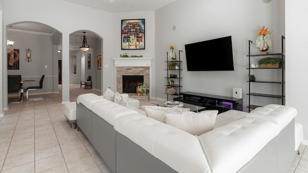 Una sala de estar moderna con un sofá grande, una chimenea, un televisor de pantalla plana y una estantería.