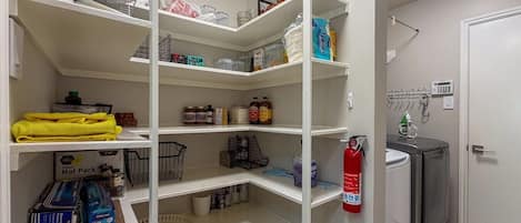 A well-organized pantry with shelves stocked with various food items and household supplies.