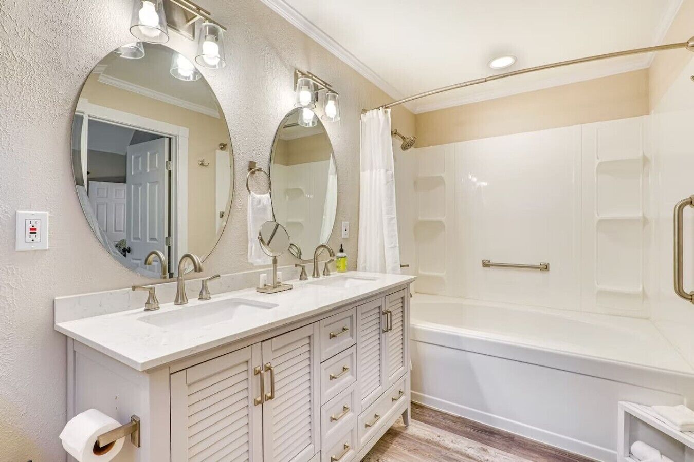 A bathroom with a double sink vanity, a large mirror, a shower with a glass door, and a towel rack.