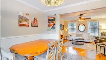 A dining area with a wooden table and chairs, a living room with a sofa and a coffee table, and a ceiling fan.