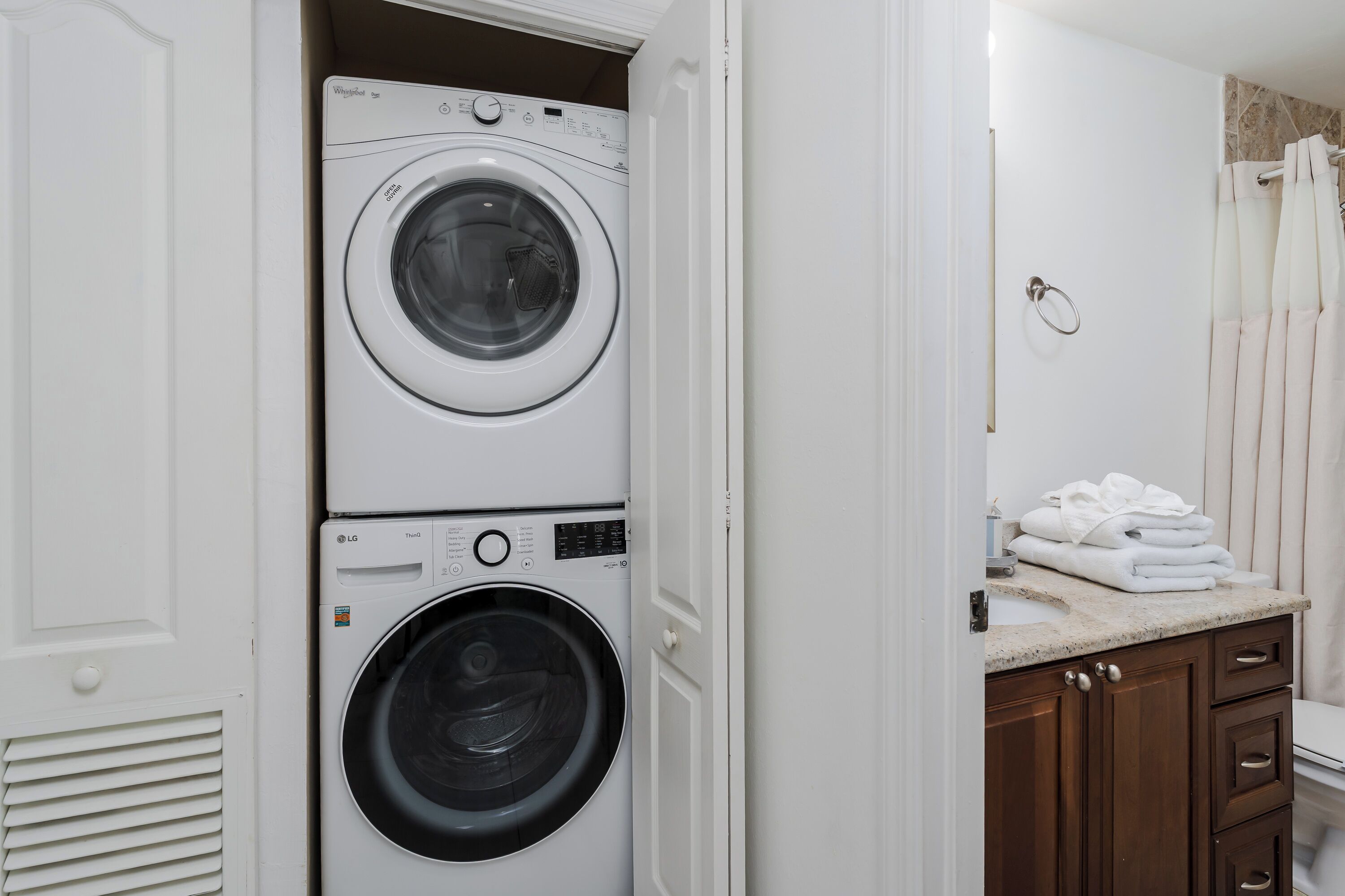A laundry room with two stacked front-loading washing machines and a countertop with towels.