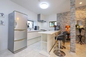 Una cocina moderna con refrigerador incorporado, cafetera y barra con taburetes.