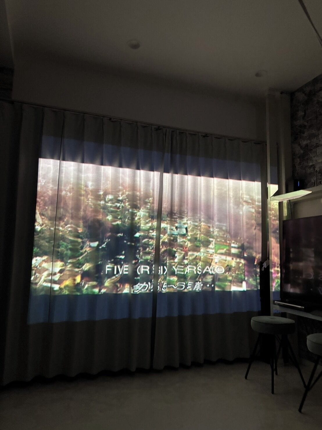 A room with a large window, a flat-screen TV, and a small table.