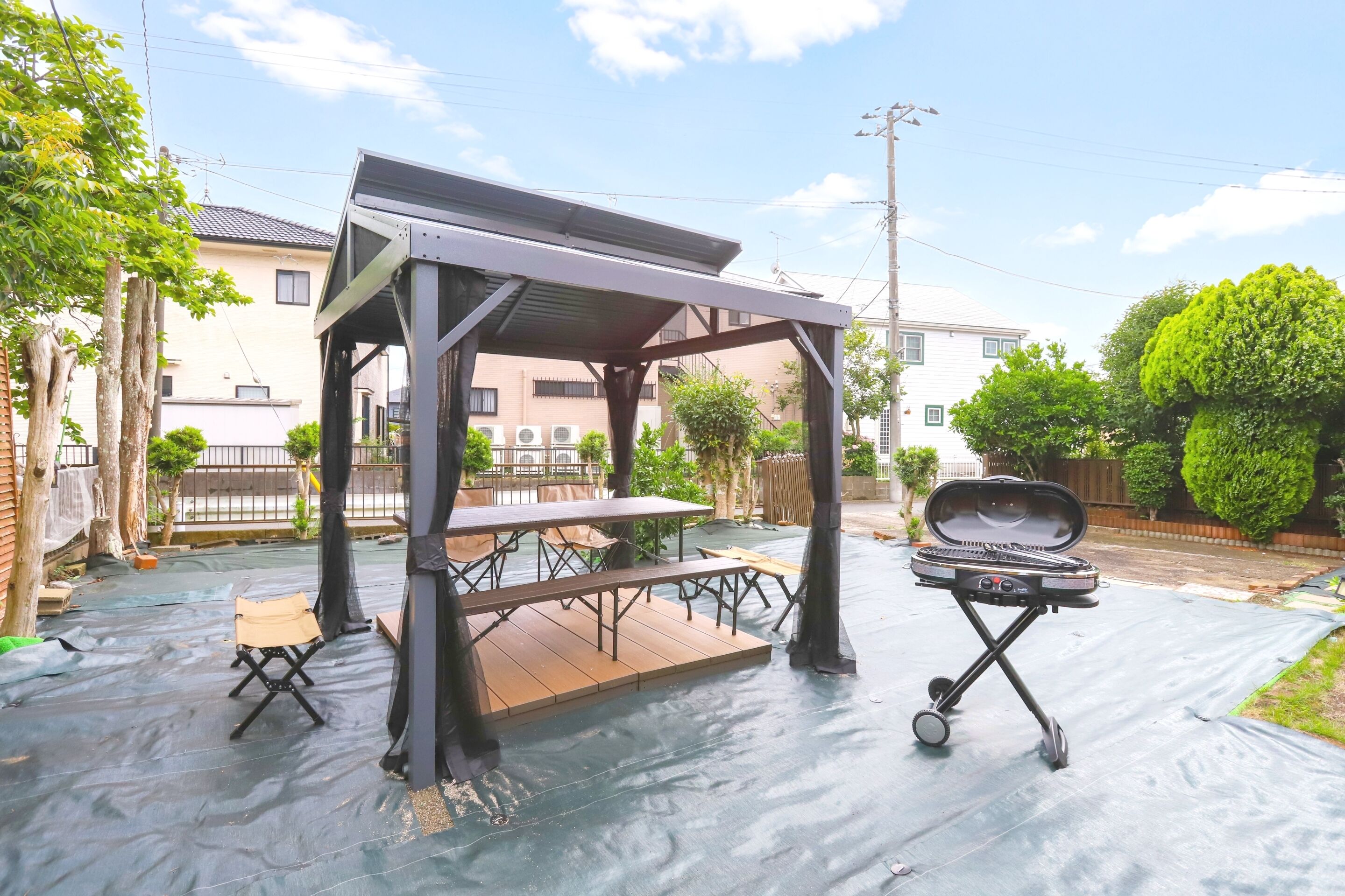 An outdoor patio with a barbecue grill and a covered seating area.