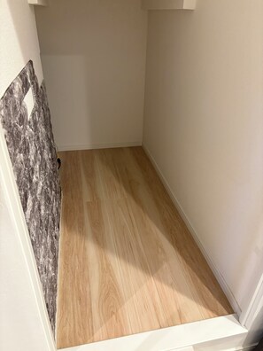 A room with a wooden floor, white walls, and a partially visible textured wall.