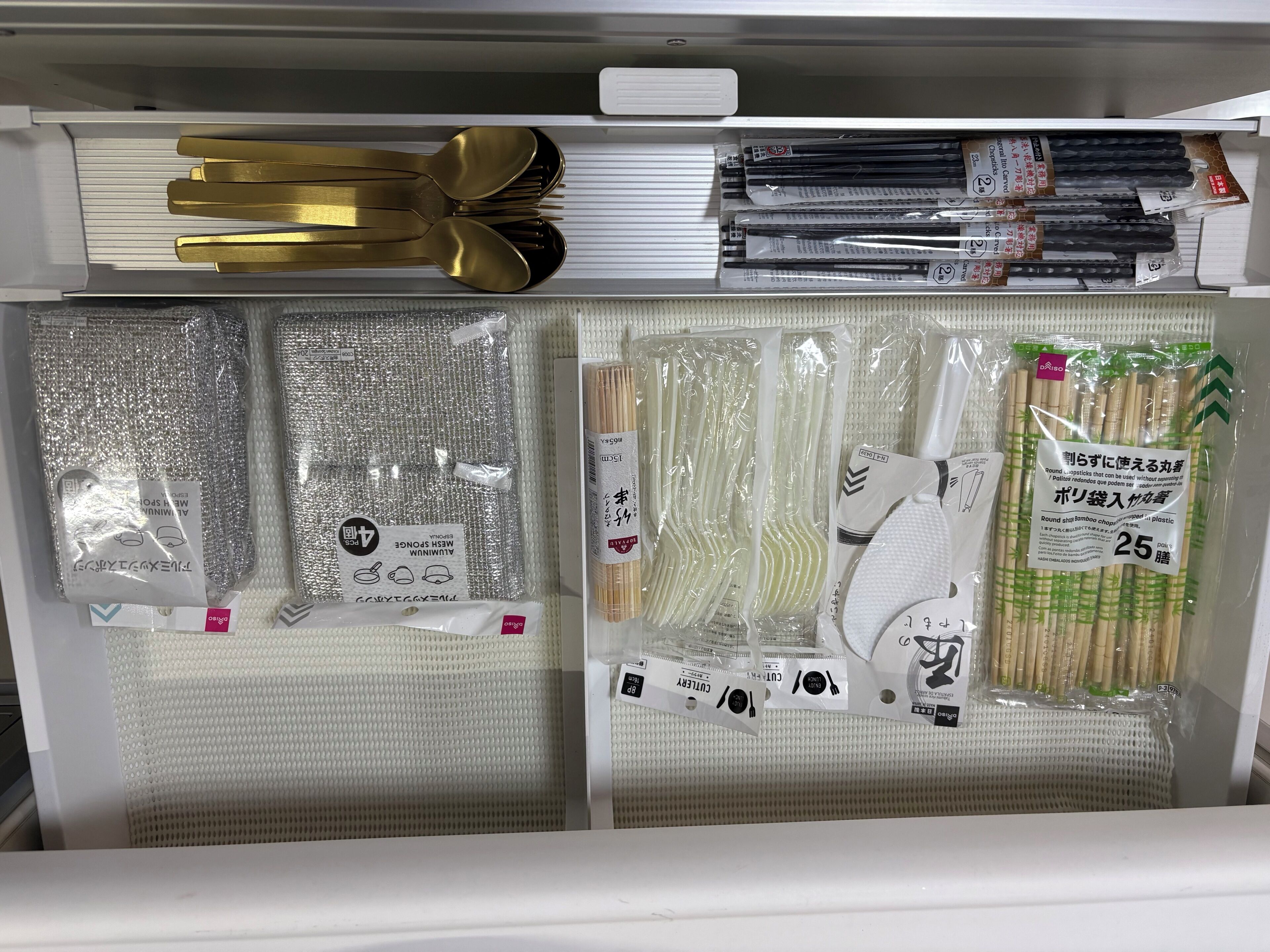 Un deposito con utensili da cucina ordinatamente organizzati, tra cui forchette, cucchiai e bacchette.