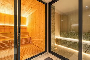 Eine moderne Sauna mit Holzwänden und einer Glastür, die in einen gefliesten Duschbereich führt.