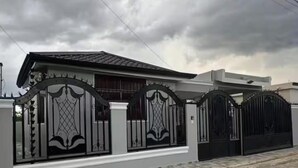 Una proprietà residenziale recintata con architettura moderna, caratterizzata da un tetto piatto e una facciata simmetrica.