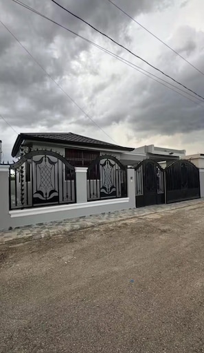 A gated residential property with a modern architectural style, featuring a flat roof and a symmetrical facade. - Luxury House in Santiago (Moca)