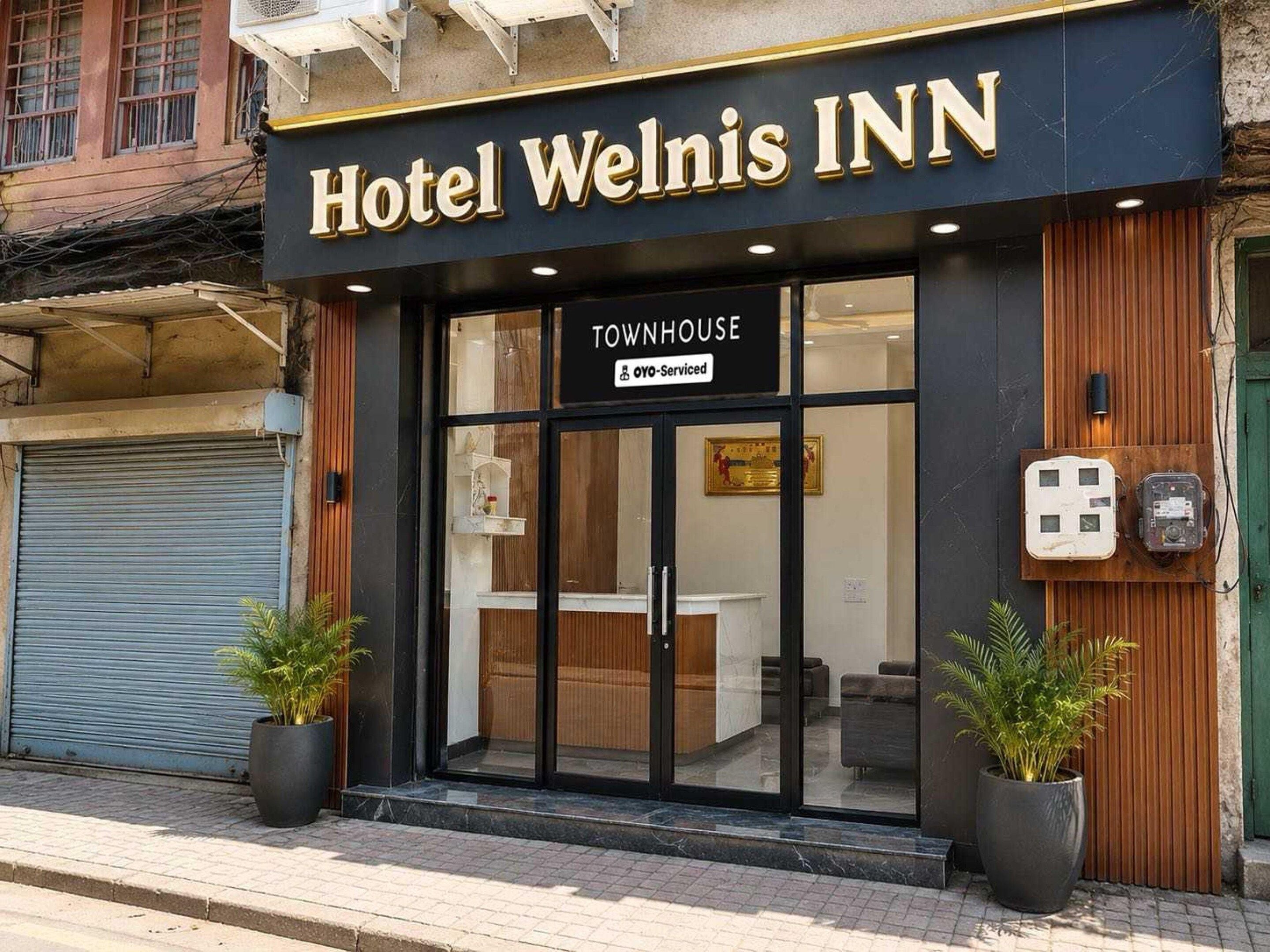 Hotel Welnis Inn with a Townhouse service, featuring a reception area with a counter and seating, and two potted plants in front.