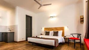 A hotel room with a bed, a desk, a chair, and a ceiling fan.