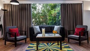A room with a black sofa, two armchairs, a coffee table, and a colorful rug.
