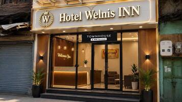 Hotel Welnis INN with a reception area, a sign indicating it is a townhouse, and air conditioning units on the exterior.