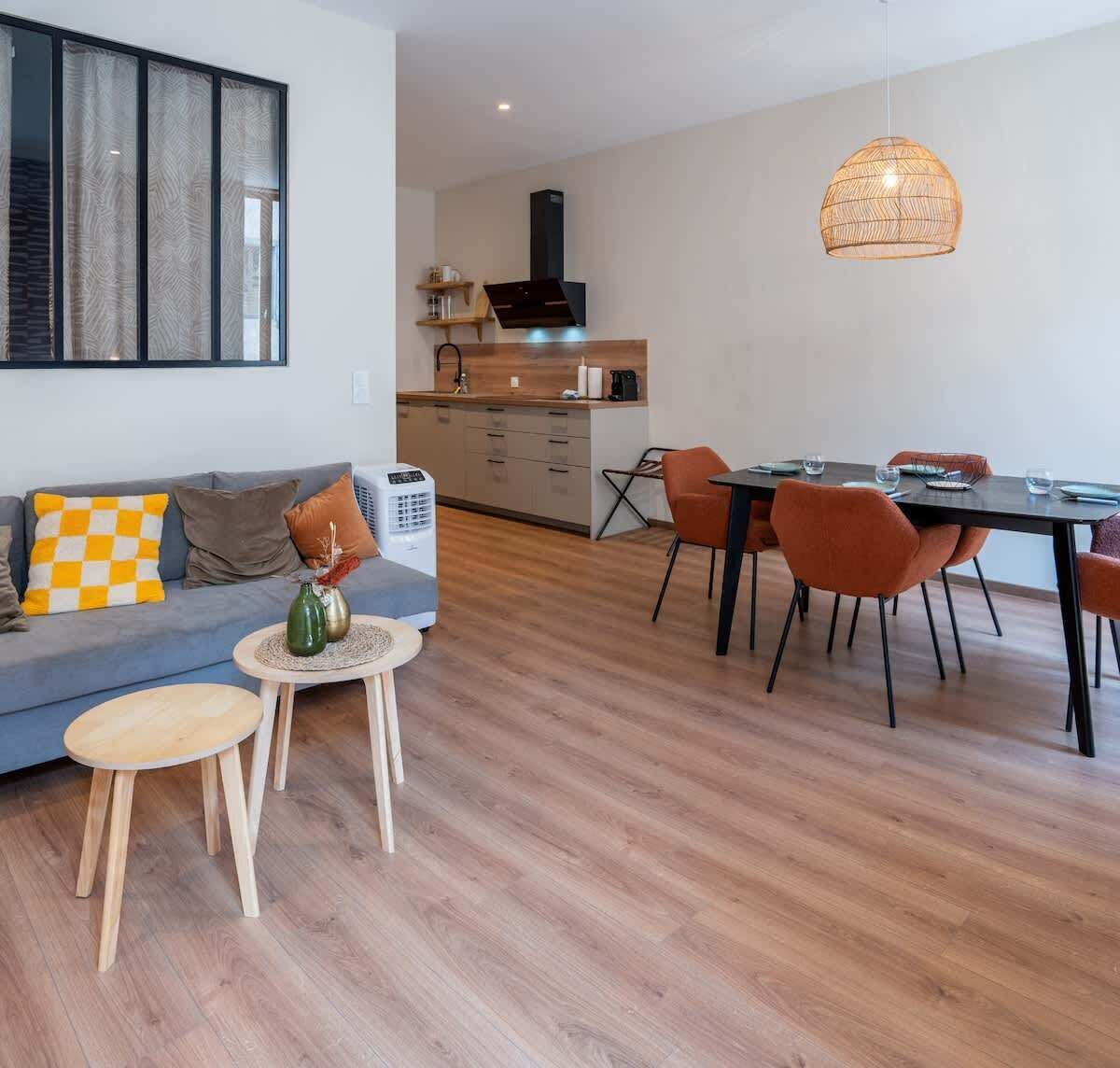 Un espace de vie moderne comprenant un canapé, une table à manger, des chaises et une petite table basse.