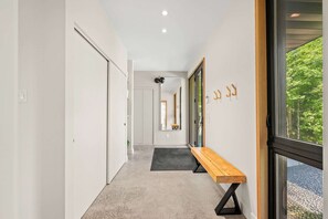 Ein Flur mit einer Bank, einem Spiegel und einer zur Zimmer führenden Tür.
