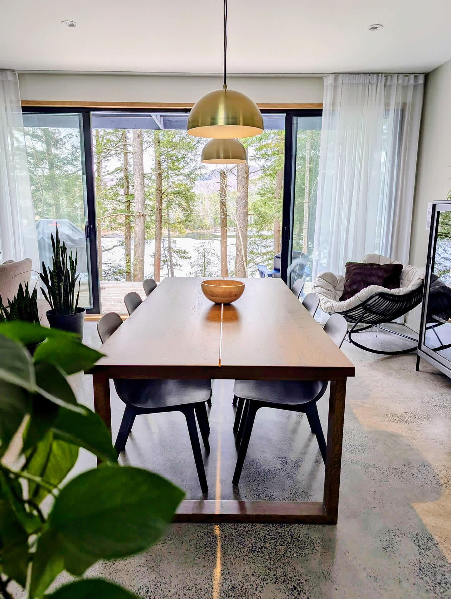 Ein zeitgemäßer Essbereich mit Holztisch, schwarzen Stühlen und einer Pendelleuchte.