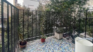 A balcony with a tiled floor, potted plants, and a mesh fence. - Charming Apartment in Recoleta 4 pax (Buenos Aires)