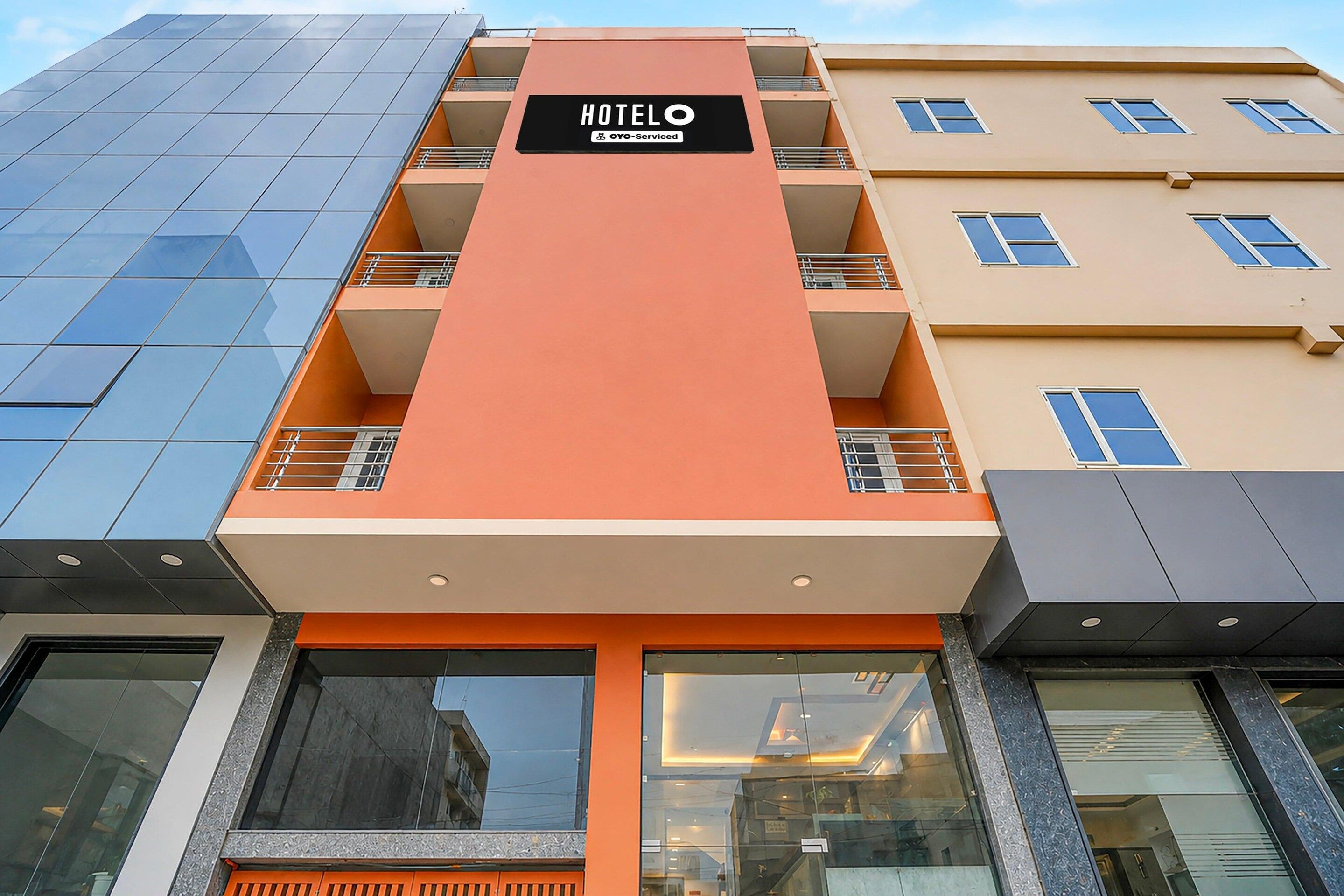 Un bâtiment d’hôtel doté d’une façade orange bien visible, de nombreux balcons et d’une enseigne indiquant qu’il est géré par OYO.