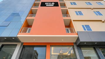 A hotel building with a prominent orange facade, multiple balconies, and a sign indicating it is serviced by OYO.