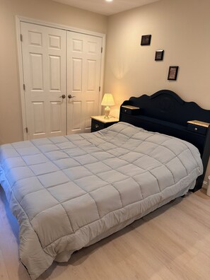Ein Schlafzimmer mit einem Bett, einem Nachttisch, einer Kommode und zwei Türen.