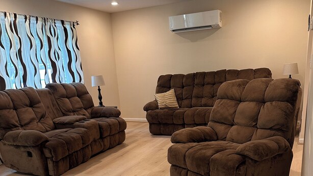 A living room with two brown recliner sofas, a lamp, and a window with patterned curtains. - Fabulous 3-bedroom house on 2 acres in quiet Garrett County wooded neighborhood (Frostburg)