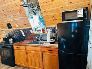 A compact kitchen with wooden cabinets, a black refrigerator, a microwave, a sink, and a kettle. - Newly built cabin by Luray Caverns/Shenandoah Natl Park/Wedding Venues (Stanley)