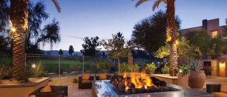 Une terrasse extérieure dotée d’un foyer, de sièges et de palmiers.
