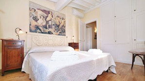 Ein Schlafzimmer mit einem Bett, einem hölzernen Schrank, einem Bild an der Wand und einer Tür zu einem anderen Raum.