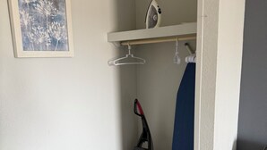 A corner of a room with a wooden floor, a white wall, a framed picture, a vacuum cleaner, and a blue chair. - Your Beachfront Getaway Awaits at Myrtle Beach SC (Myrtle Beach)