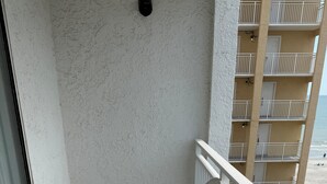 A balcony with white plastic chairs, a metal table, and a view of a beach and ocean. - Your Beachfront Getaway Awaits at Myrtle Beach SC (Myrtle Beach)