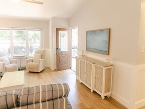 A spacious living room with a sofa, armchairs, a coffee table, and a cabinet. There is a door leading to another room and a painting on the wall. - Happy Days in Cape May (Cape May)