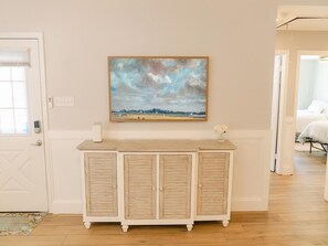 Ein Zimmer mit einem Holzkasten, einem Bild an der Wand und einem Bett im Hintergrund.