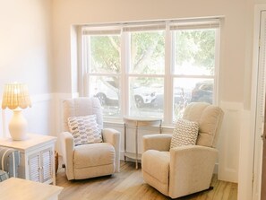 A room with two armchairs, a small table, and a lamp. There is a window with a view of parked cars outside. - Happy Days in Cape May (Cape May)