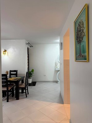A dining area with a table and chairs, a potted plant, and a wall-mounted light fixture. - Fantastic 3-bedroom apartment in Embakasi Nairobi perfect for your stay (Embakasi, nairobi)