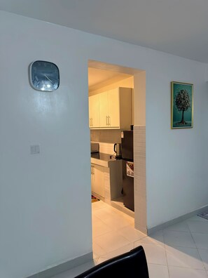 Een moderne keuken met witte kasten, een koelkast en een klok aan de muur.
