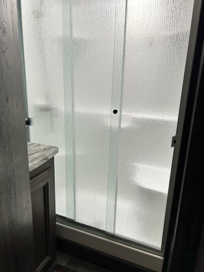 Ein Zimmer mit einer Tür aus Milchglas, einem Holzschrank und einem gefliesten Boden.