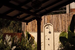 A covered outdoor area with a door, bamboo wall, and various plants.