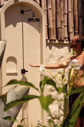 A person reaching out to a wall-mounted showerhead.